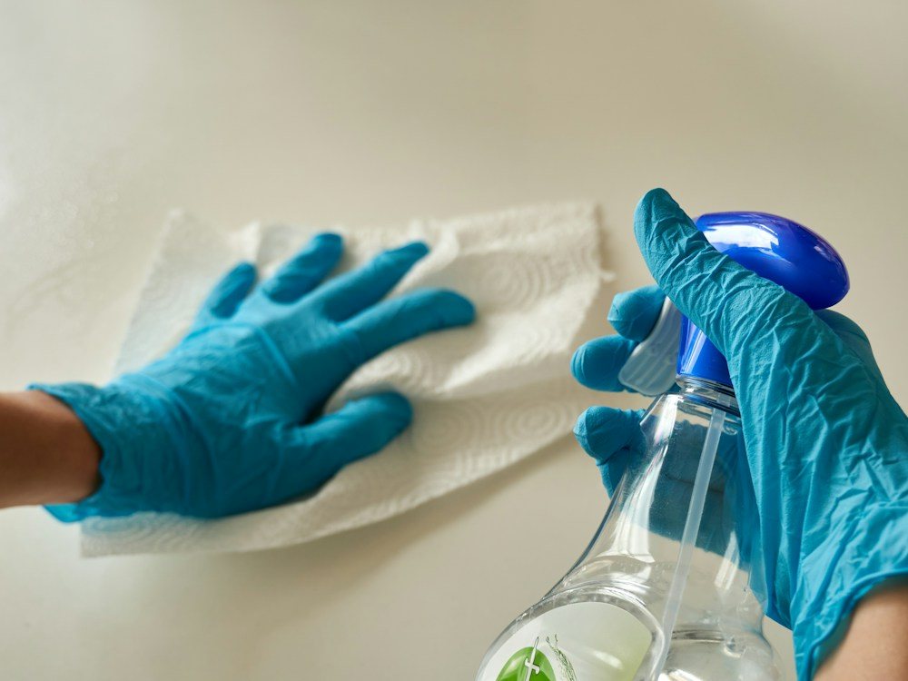 Gloved hands cleaning a surface